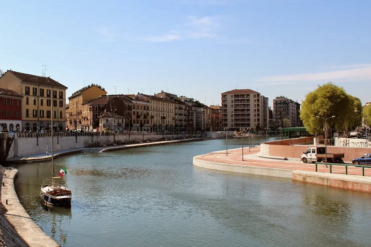 The Darsena basin in Milan on a clear day, with apartment buildings along the quay